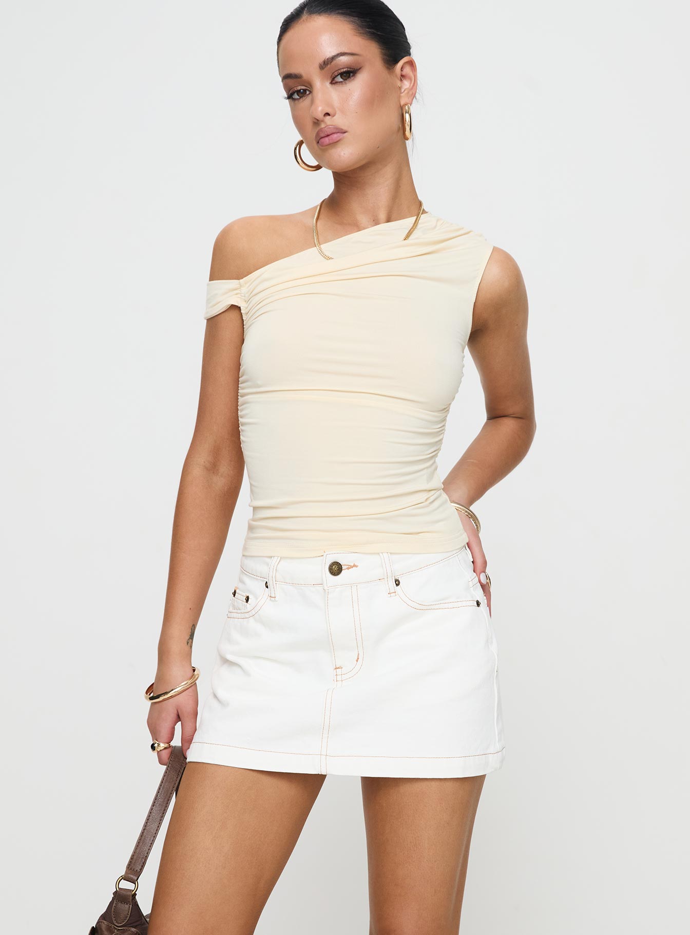   side view of model wearing Princess Polly Nicolina Low Rise Denim Mini Skirt Ecru Mini Skirts 